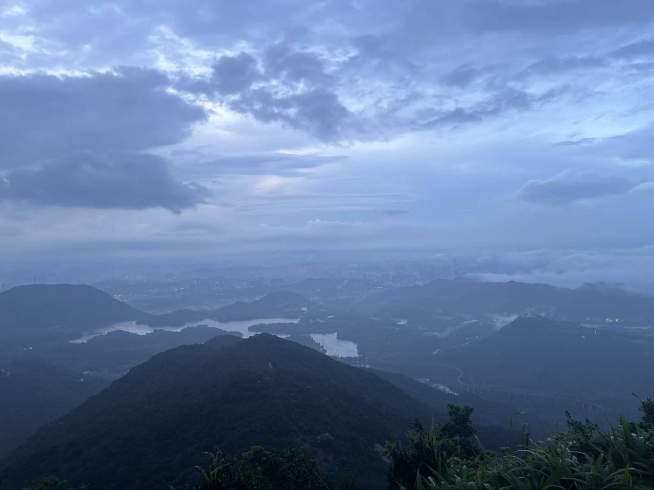 雨后从梅沙尖高处远望，连绵山脊与谷地水面在散去的云雾中显出轮廓