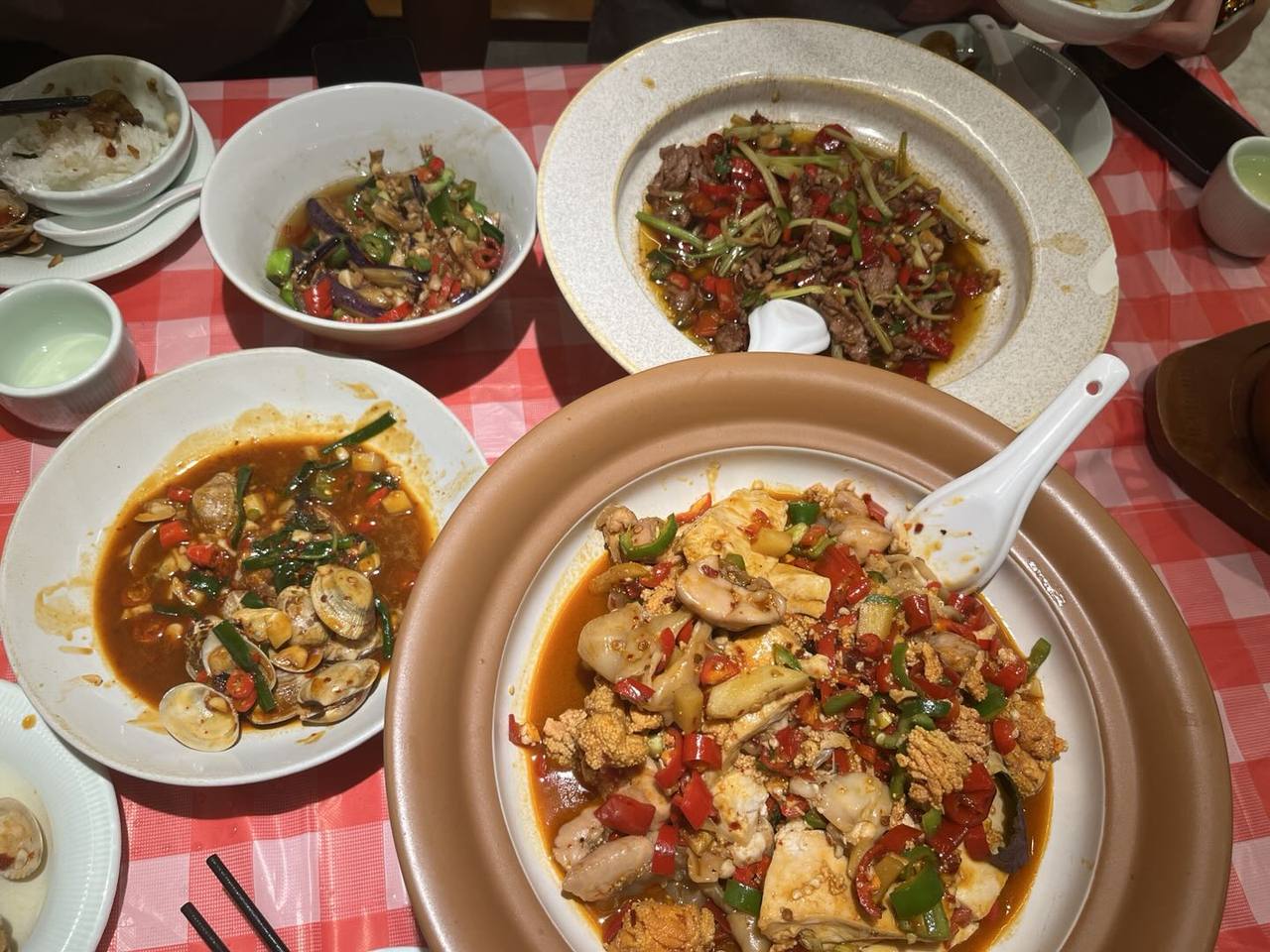 红白格桌布上的共享晚餐,辣味热菜与花甲围在桌边