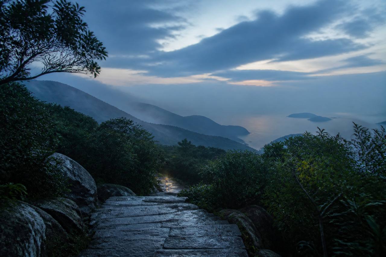 雨后山脊间延伸的湿润石阶与远处海面