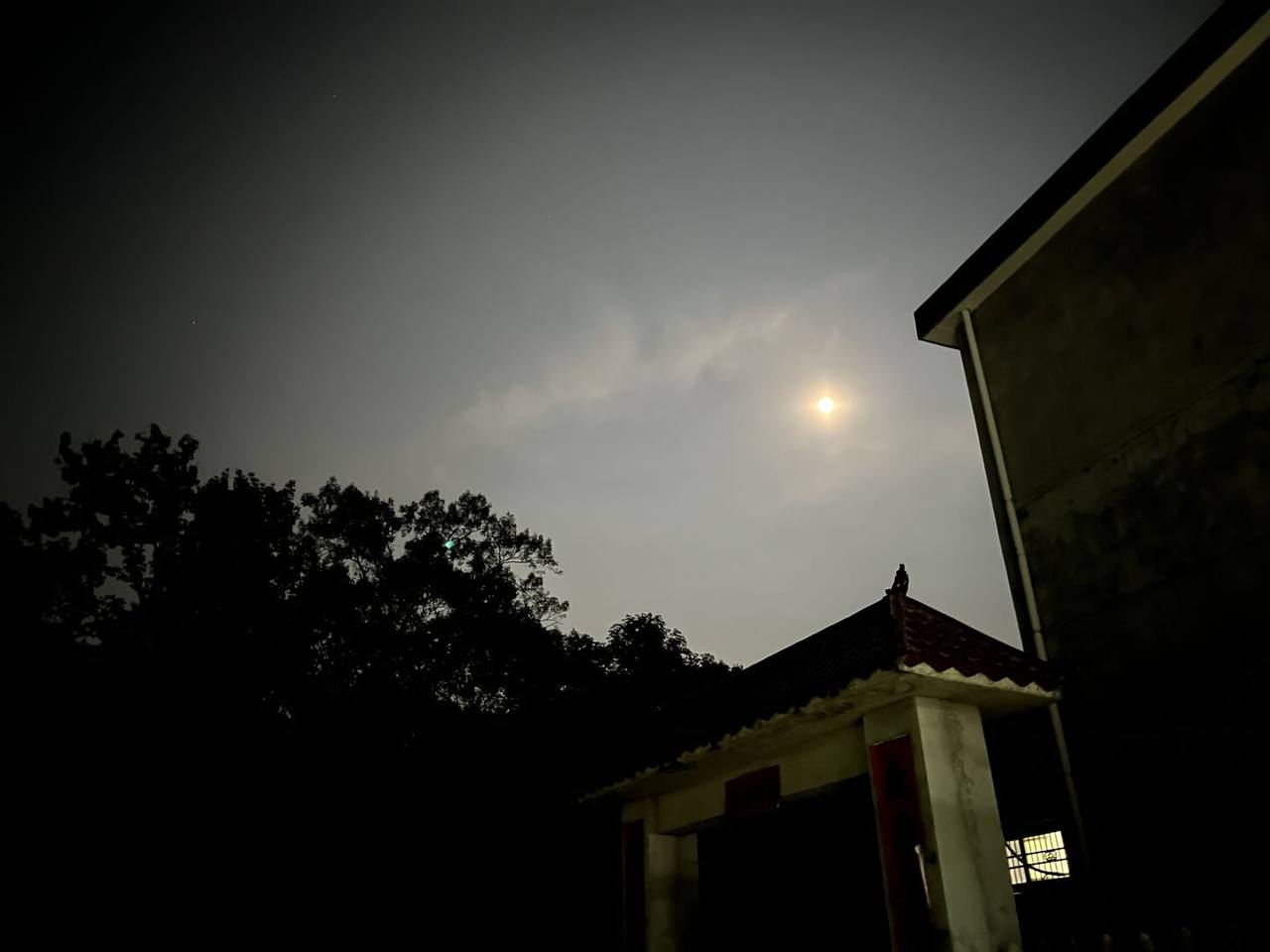 薄云笼住月亮，树影与旧屋檐沉入安静夜色